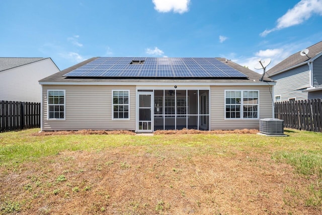 rear view of house featuring roof mounted solar panels, a sunroom, and central AC
