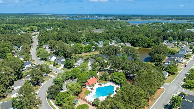 aerial view of property and surrounding area with a pool, a forest, nearby suburban area, and a nearby body of water