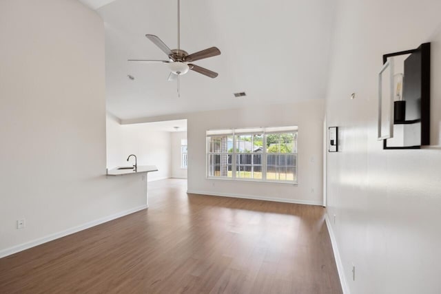 unfurnished living room with high vaulted ceiling, wood finished floors, baseboards, and ceiling fan