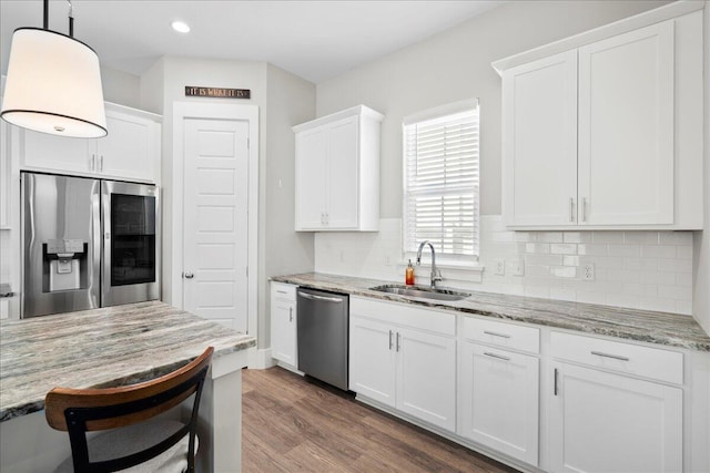 kitchen featuring sink, white cabinetry, light stone counters, pendant lighting, and stainless steel appliances