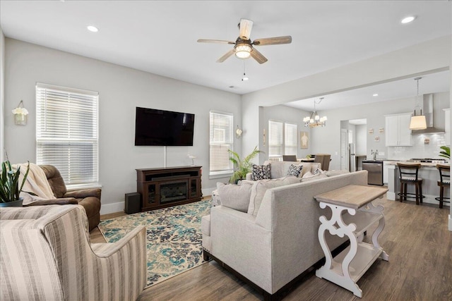 living room with a wealth of natural light, dark hardwood / wood-style floors, and ceiling fan with notable chandelier