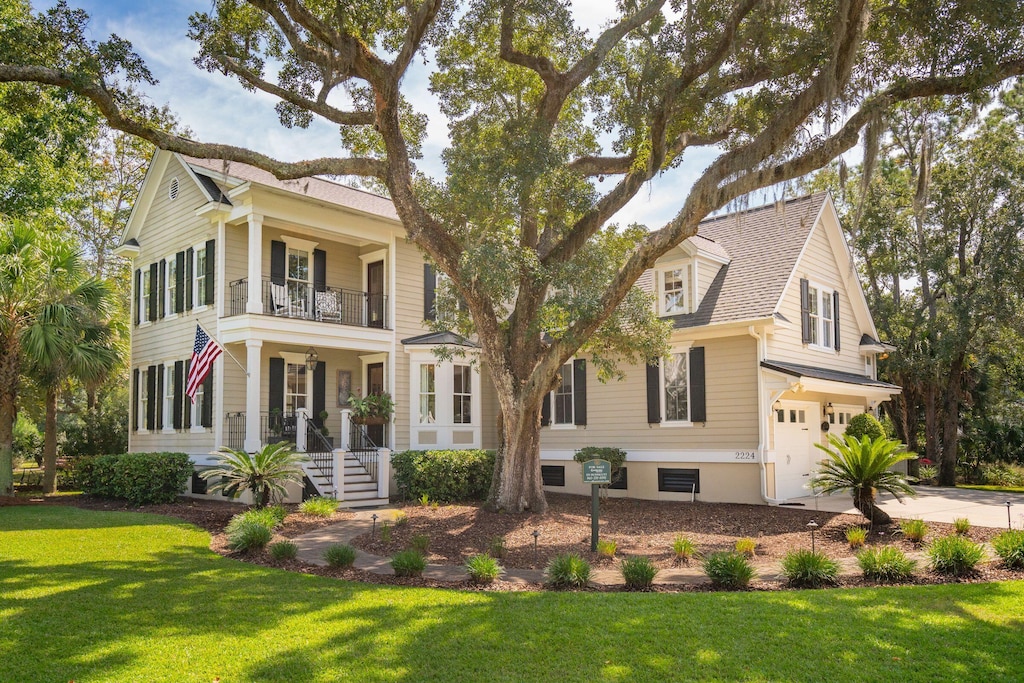 view of front of property with a porch, a balcony, a garage, and a front lawn