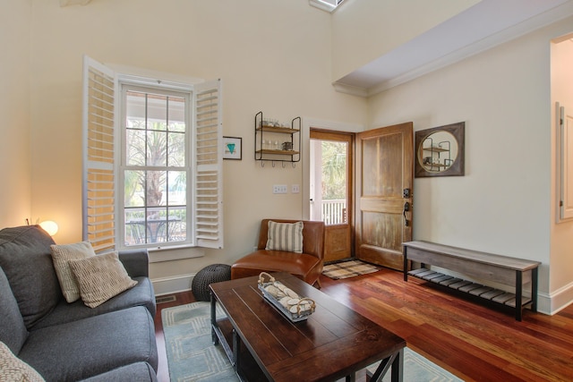 living area featuring crown molding, wood finished floors, and baseboards