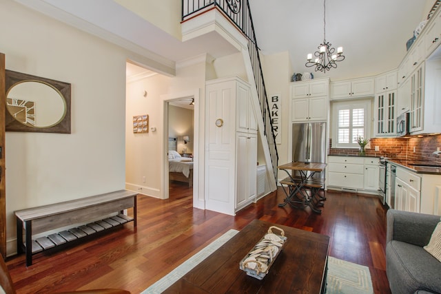 living area with baseboards, visible vents, dark wood finished floors, a towering ceiling, and an inviting chandelier