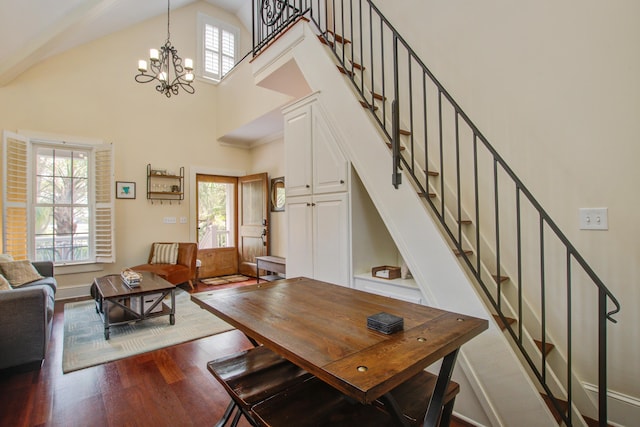 dining space with an inviting chandelier, wood finished floors, high vaulted ceiling, baseboards, and stairs