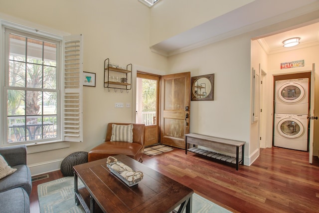 living area with stacked washer and clothes dryer, visible vents, plenty of natural light, and wood finished floors