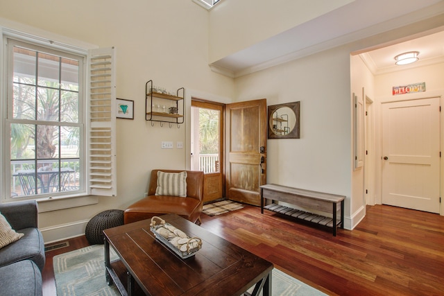 living room featuring ornamental molding, wood finished floors, visible vents, and baseboards