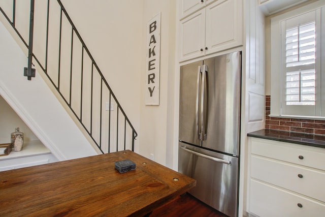 kitchen featuring wooden counters, decorative backsplash, freestanding refrigerator, and white cabinets