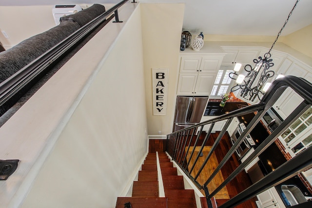 staircase with an inviting chandelier and wood finished floors