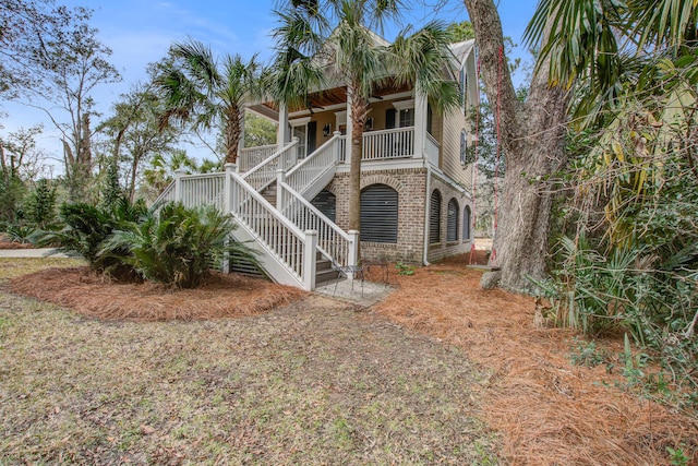 back of house featuring covered porch, brick siding, and stairway