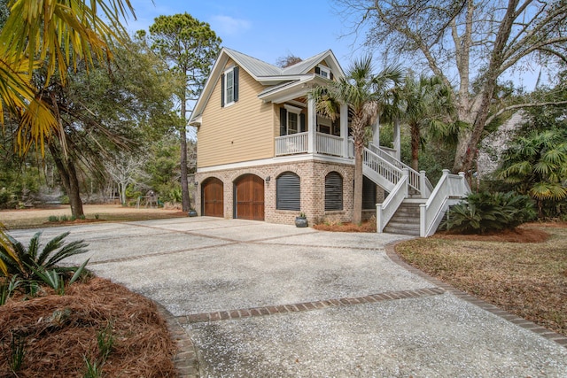 view of front of property featuring driveway, covered porch, and stairs