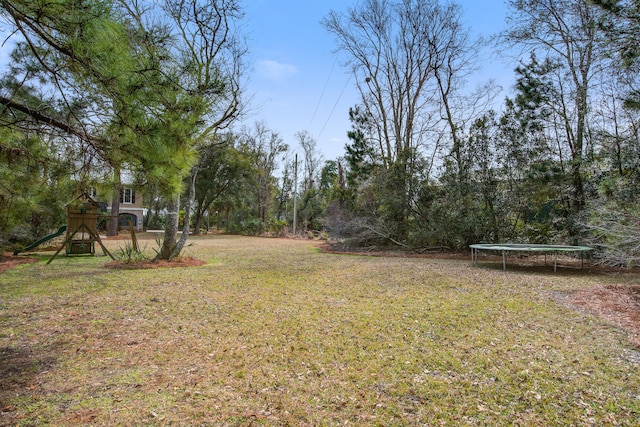 view of yard featuring playground community and a trampoline