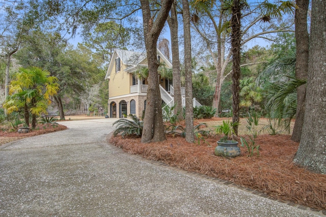 view of side of property featuring driveway, brick siding, and stairway