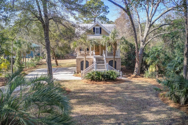 beach home with metal roof, a standing seam roof, stairs, a porch, and brick siding