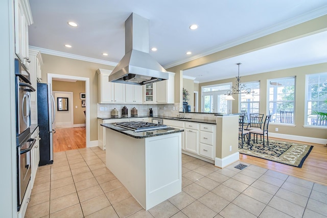 kitchen featuring light tile patterned floors, a peninsula, freestanding refrigerator, tasteful backsplash, and island exhaust hood