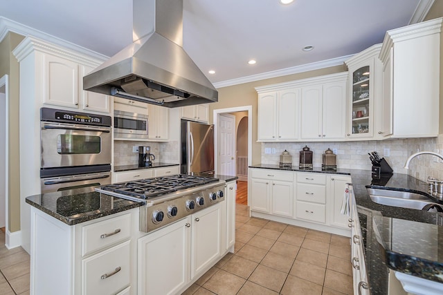 kitchen with light tile patterned floors, island range hood, appliances with stainless steel finishes, ornamental molding, and a sink