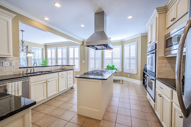 kitchen with light tile patterned floors, island range hood, appliances with stainless steel finishes, crown molding, and a sink