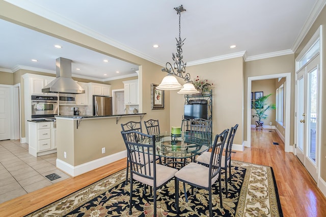 dining room with baseboards, light wood-type flooring, and crown molding