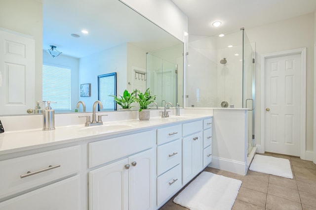 bathroom with double vanity, a stall shower, a sink, and tile patterned floors