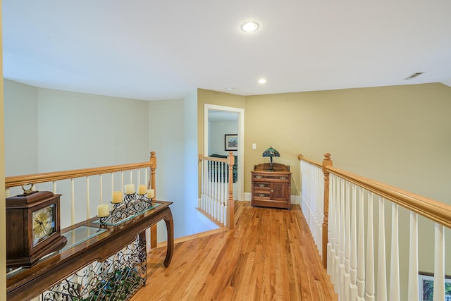 hall with recessed lighting, wood finished floors, visible vents, an upstairs landing, and baseboards