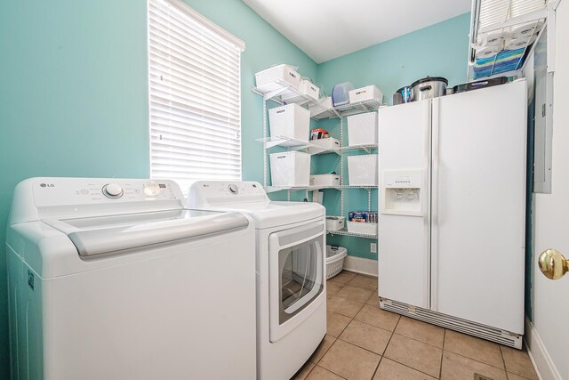 clothes washing area featuring laundry area, baseboards, washer and dryer, and light tile patterned flooring