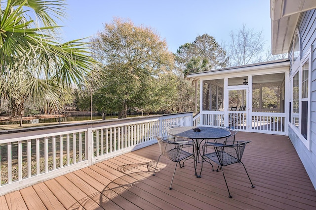 wooden terrace featuring outdoor dining area and a sunroom