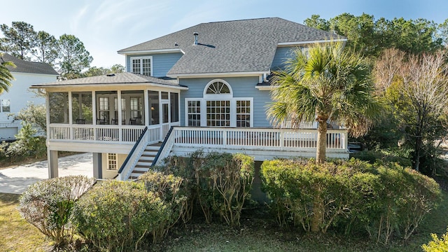 rear view of house with roof with shingles, stairway, and a sunroom