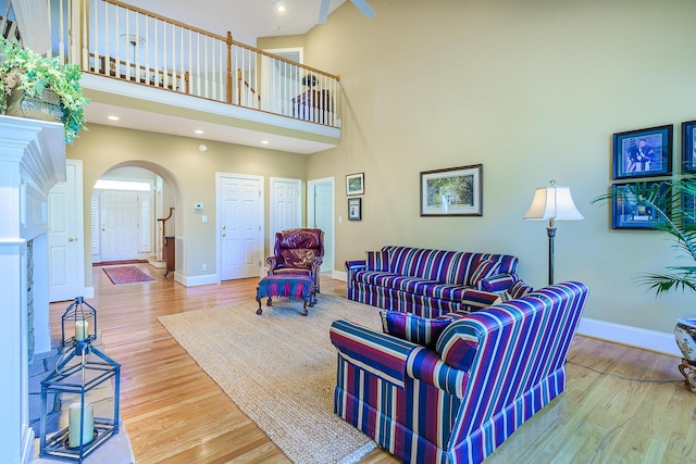 living room with arched walkways, a high ceiling, baseboards, and wood finished floors