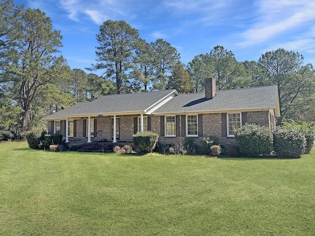 single story home with brick siding, roof with shingles, a chimney, a porch, and a front yard