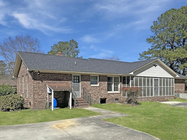 back of house featuring a shingled roof, a sunroom, a chimney, a yard, and brick siding