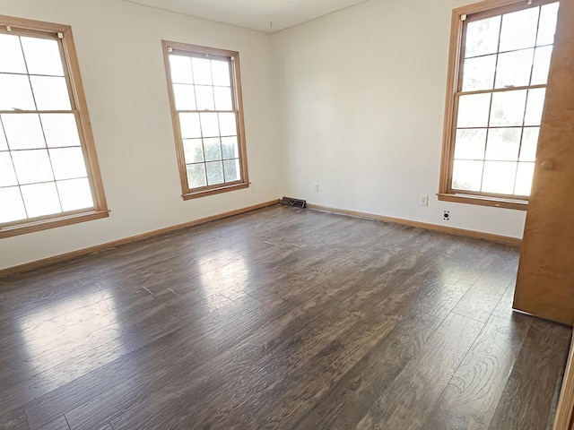 spare room with visible vents, baseboards, and dark wood-style flooring