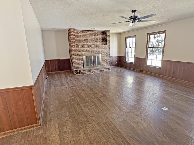 unfurnished living room featuring a wainscoted wall, a fireplace, and wood finished floors