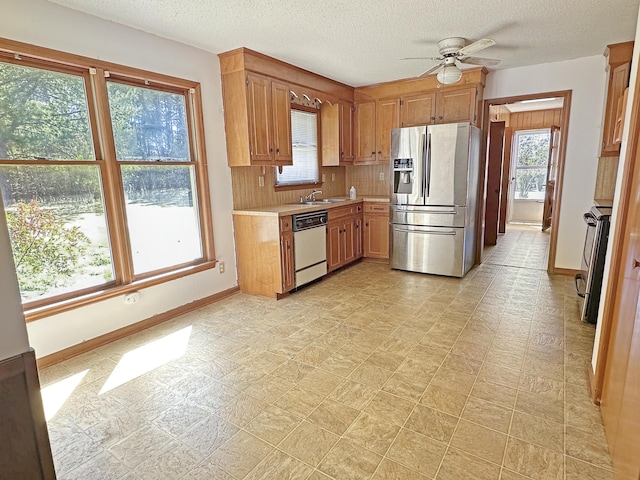 kitchen featuring light countertops, decorative backsplash, stainless steel fridge, dishwasher, and baseboards