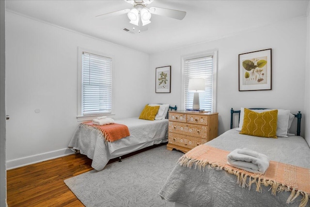 bedroom featuring multiple windows, dark hardwood / wood-style floors, and ceiling fan