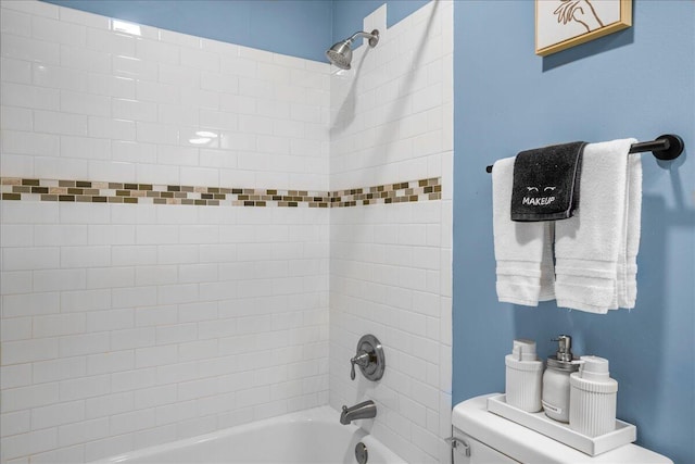 bathroom with tiled shower / bath combo and toilet