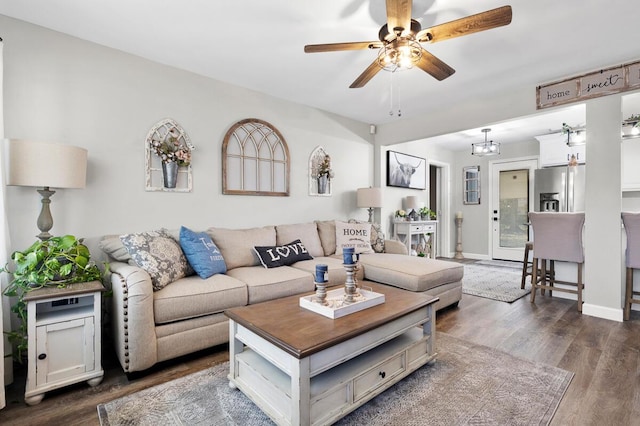 living room with dark wood-style flooring, a ceiling fan, and baseboards