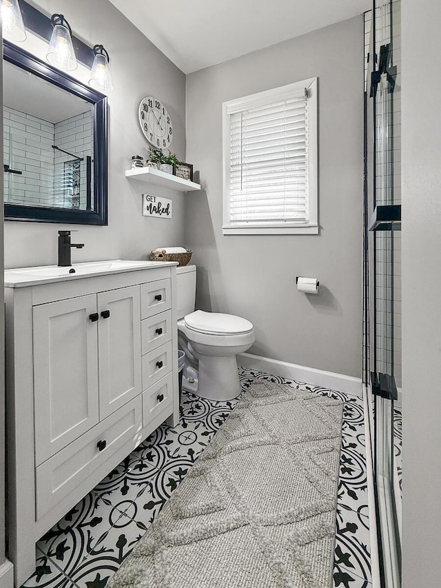 bathroom featuring a shower, toilet, vanity, tile patterned flooring, and baseboards