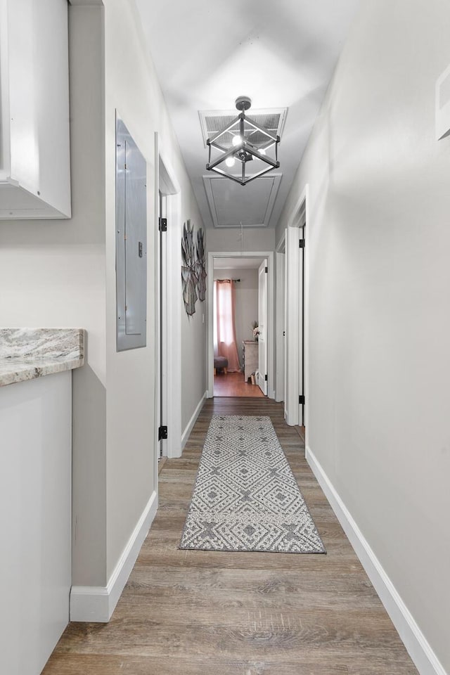 hallway with attic access, electric panel, visible vents, baseboards, and light wood-style floors