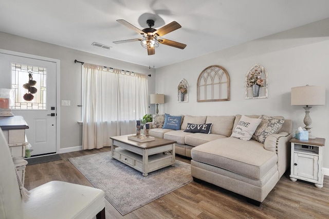 living area featuring dark wood-style floors, visible vents, ceiling fan, and baseboards