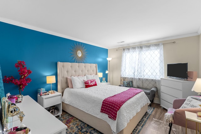 bedroom featuring visible vents, wood finished floors, and crown molding