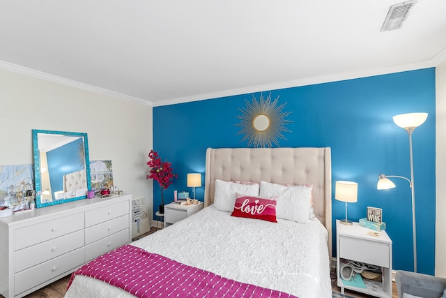 bedroom featuring visible vents, wood finished floors, and ornamental molding