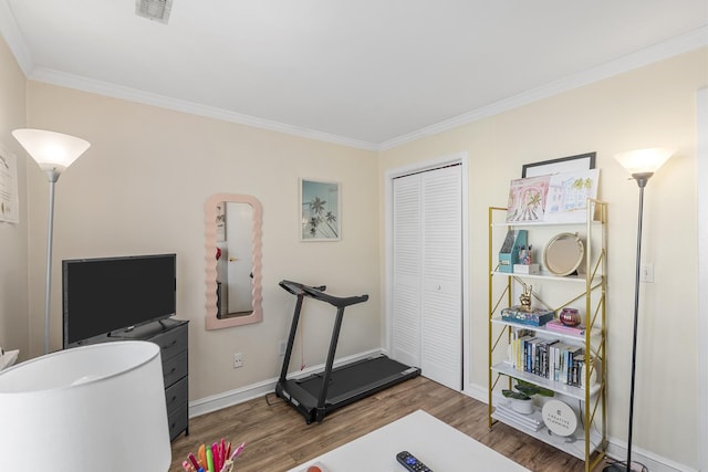 exercise room featuring ornamental molding, wood finished floors, visible vents, and baseboards