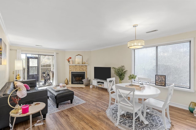 living room with visible vents, ornamental molding, a brick fireplace, and wood finished floors