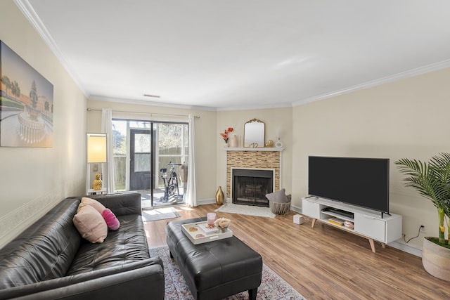 living room featuring wood finished floors, visible vents, baseboards, a fireplace, and ornamental molding