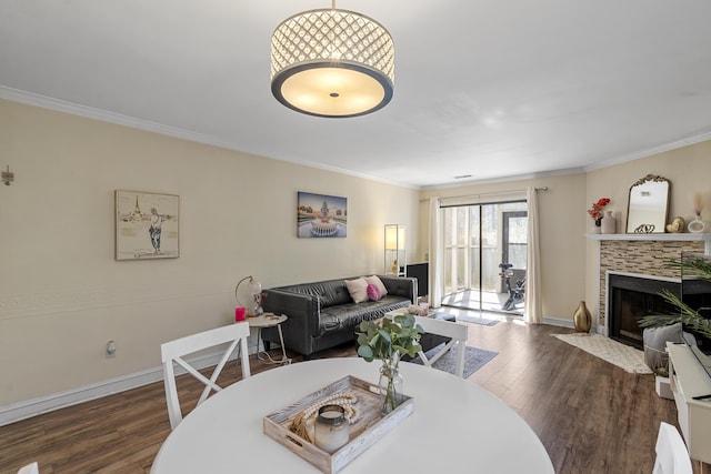 dining area featuring baseboards, dark wood-type flooring, ornamental molding, and a tile fireplace