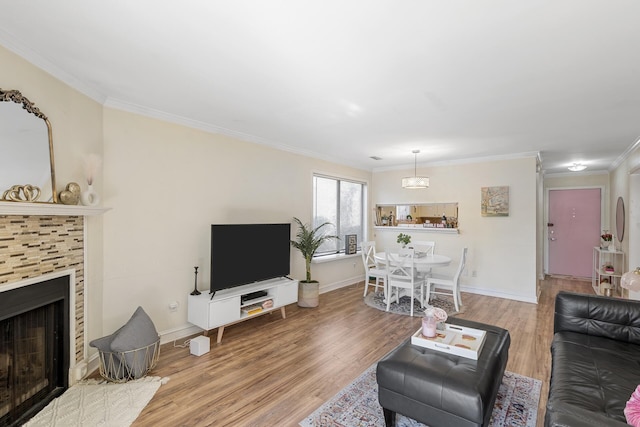 living room featuring baseboards, wood finished floors, a fireplace, and crown molding