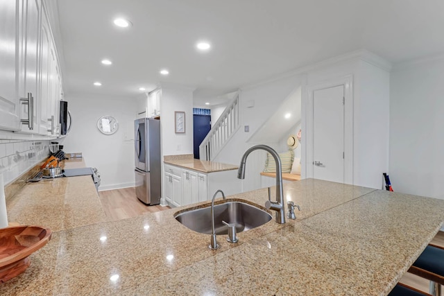 4 Beach Club Villas, Isle Of Palms, SC 29451 - kitchen featuring stainless steel appliances, a sink, tasteful backsplash, white cabinets, and light wood-style flooring