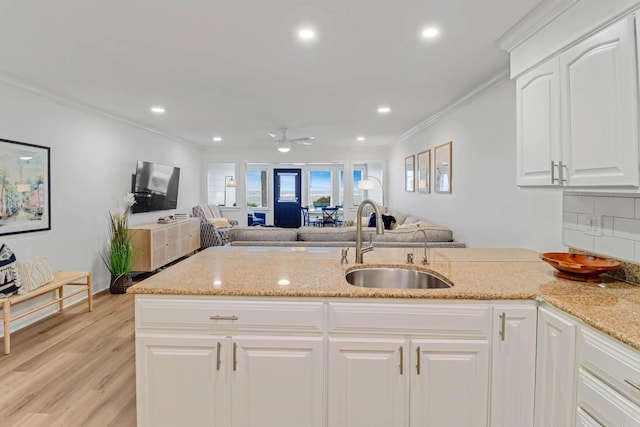 4 Beach Club Villas, Isle Of Palms, SC 29451 - kitchen with a sink, light stone counters, light wood-style flooring, ornamental molding, and decorative backsplash
