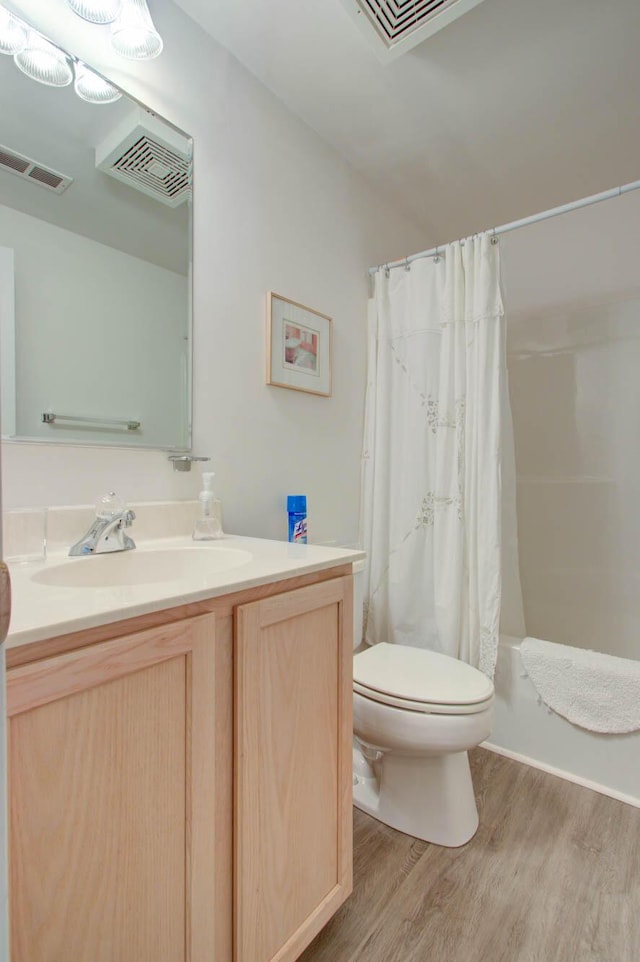 bathroom with vanity, toilet, wood finished floors, and visible vents