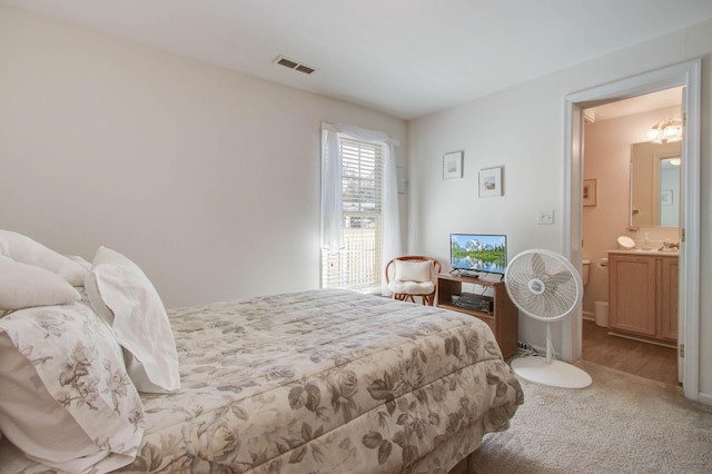 bedroom with visible vents, carpet floors, and ensuite bathroom